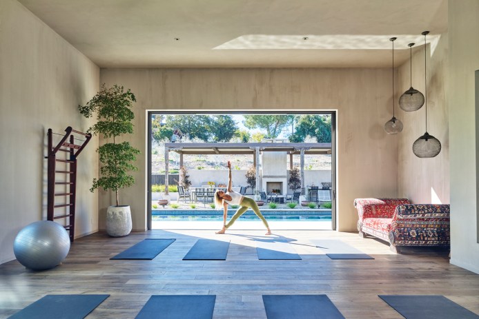 Woman in a yoga pose in a room overlooking a pool