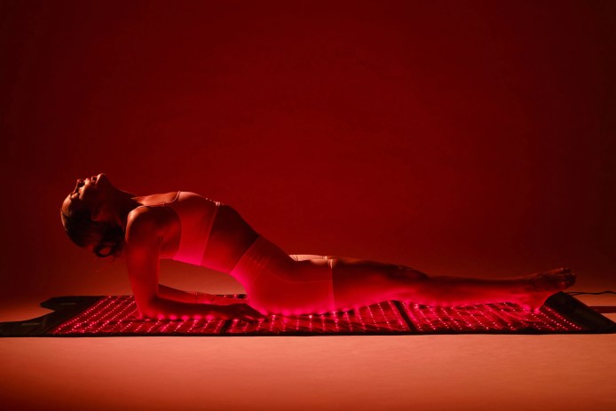 Woman in a yoga pose on a red light therapy mat