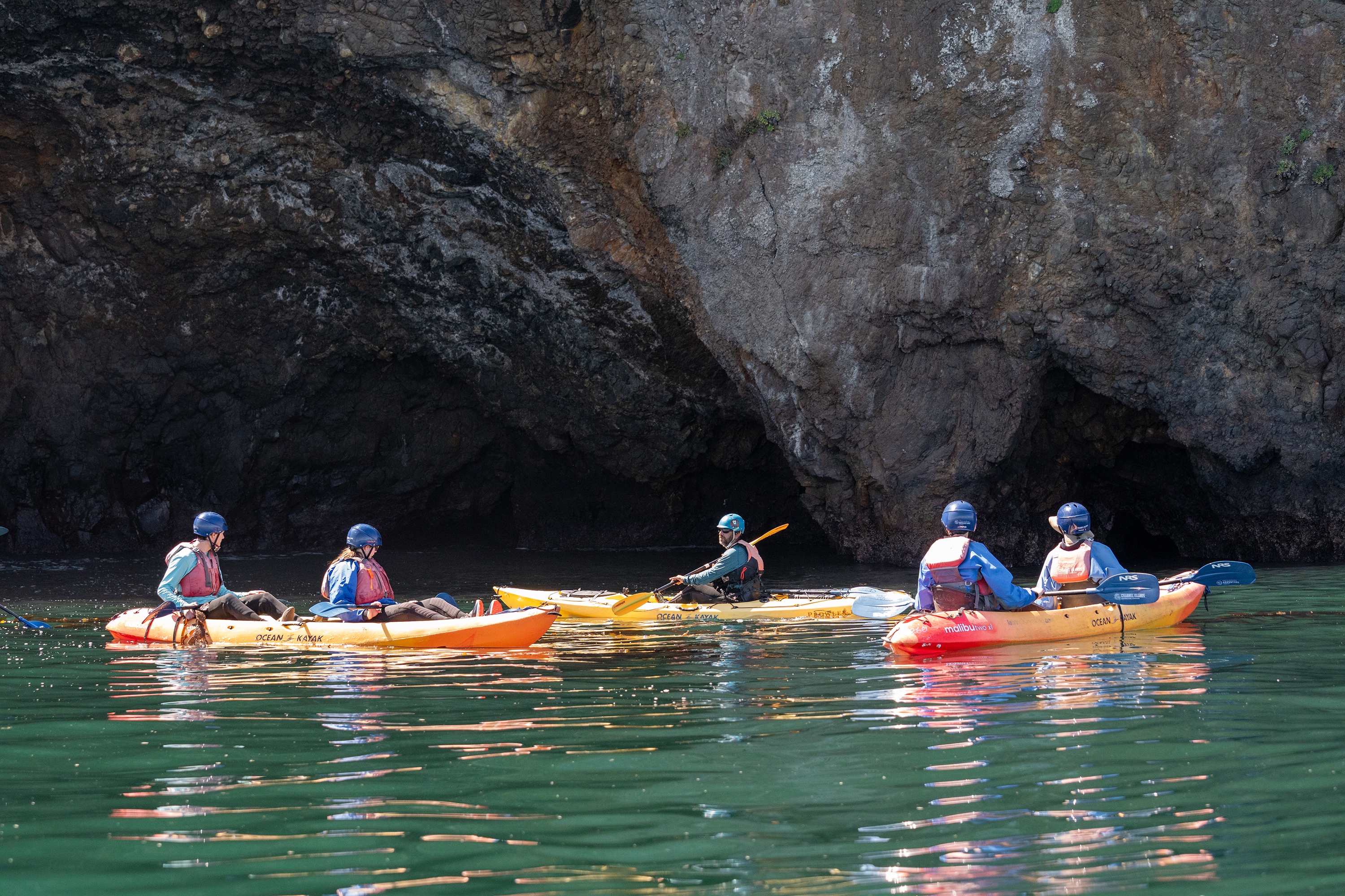 kayakers-float-at-the-entrance-of-sea-caves-carved-into-volcanic-rock-at-channel-islands-national-park