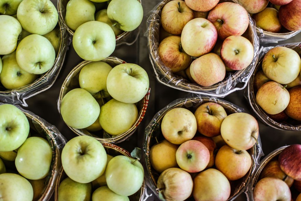 Green and red apple varieties in wooden baskets.