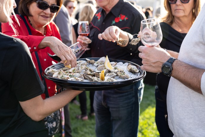 People eating oysters and drinking wine.
