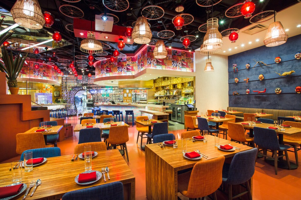 China Poblano’s colorful dining room features wooden tables, blue and orange chairs, red lanterns, and bicycle wheels overhead.