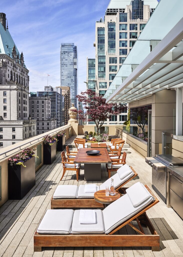 An outdoor dining and lounge area on a balcony overlooking downtown Vancouver.