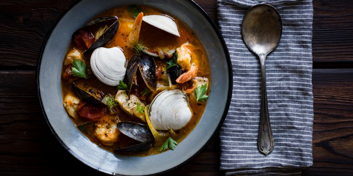 Bowl of cioppino with napkin and spoon
