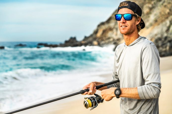 man standing on beach with fishing rod
