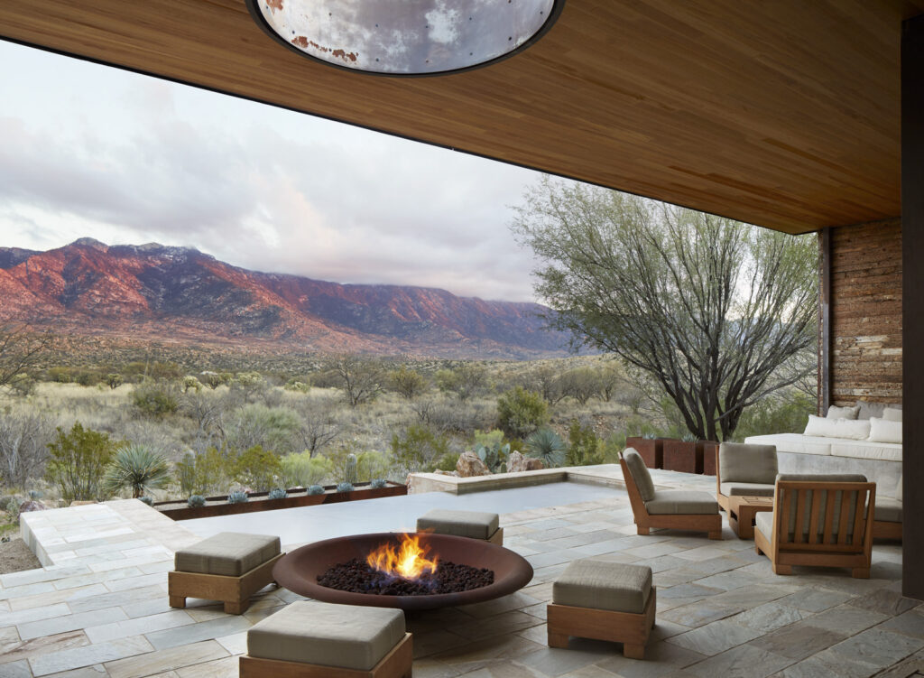 A patio with furniture and a fire feature overlooking the mountains.