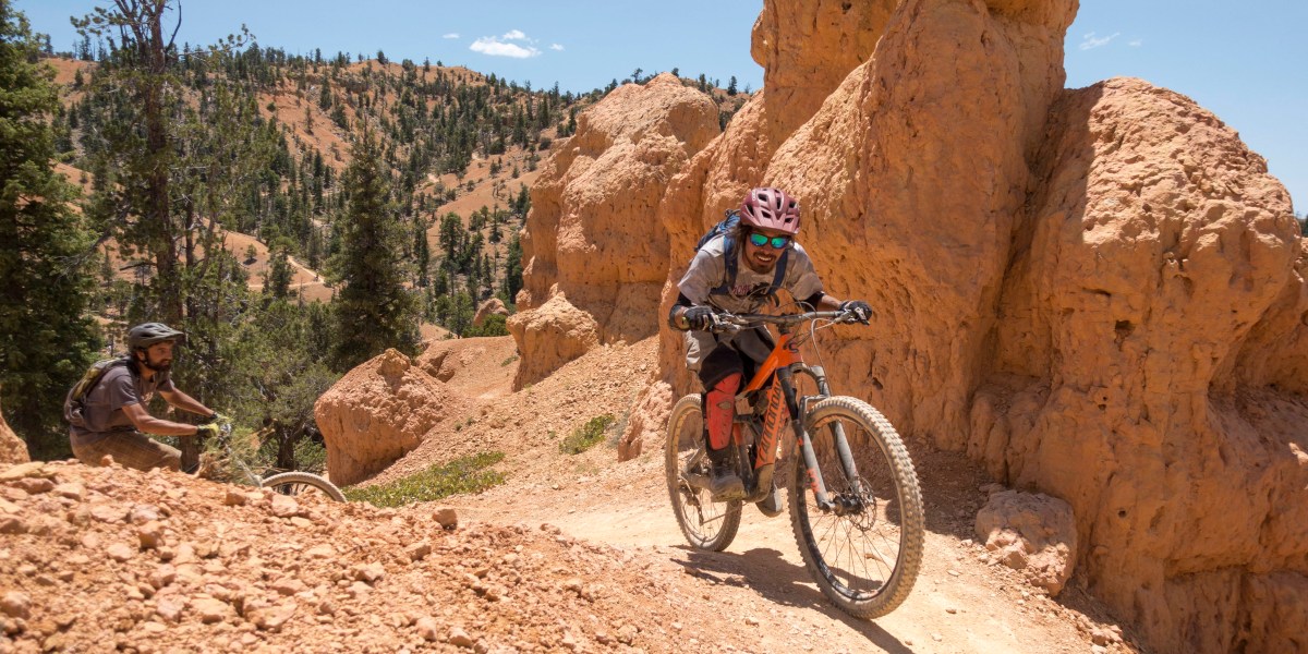 mountain bikers riding through off-road terrain among red rocks and trees