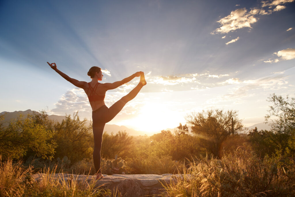 A woman doing a yoga pose on a ranch.