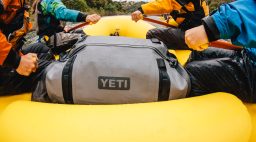 rowers on a raft sit on either side of a dry bag
