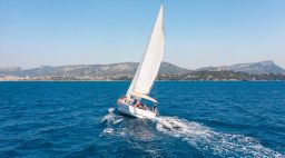 sale boat on the ocean with coastline in the background