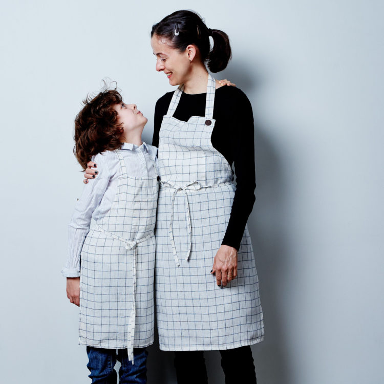 Caucasian mother and son wearing aprons in kitchen mother tying