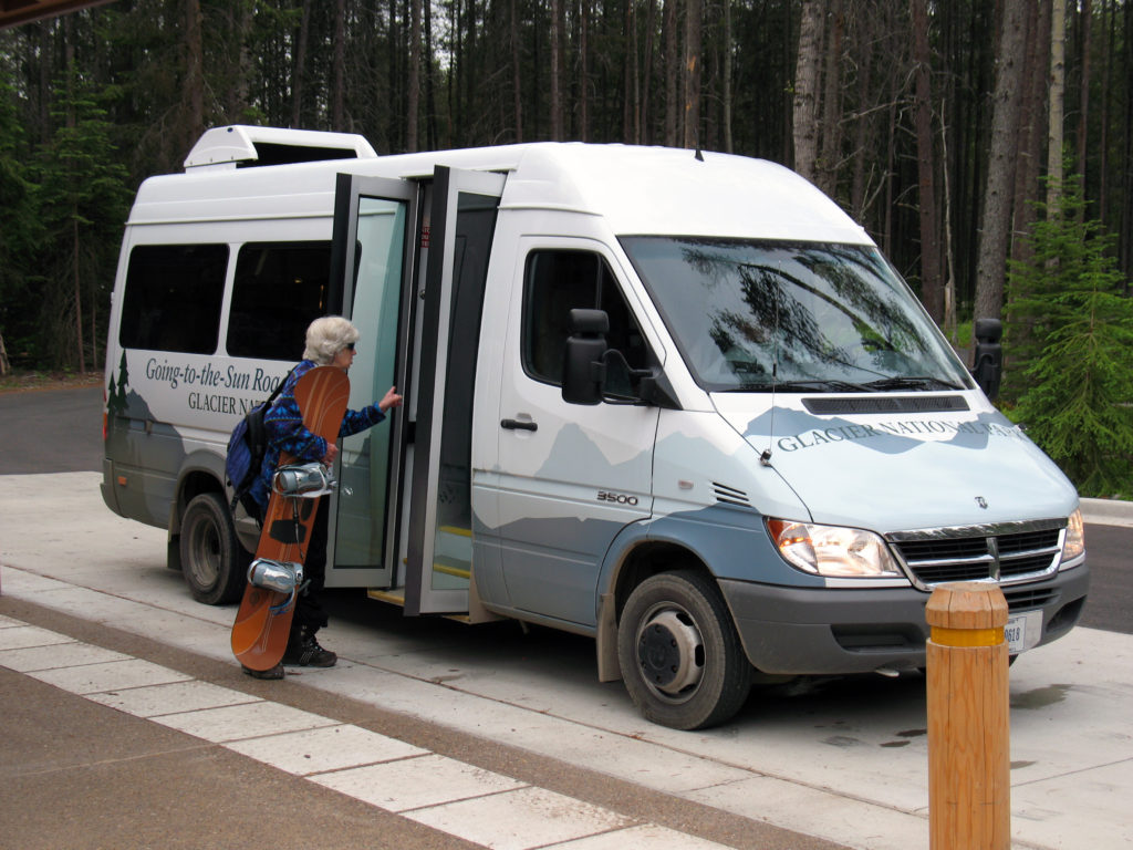 elderly woman holding snowboard boards shuttle bus