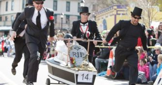 Men in pallbearer costumes racing with a fake coffin in the Emma Crawford Halloween events in Manitou Springs, CO