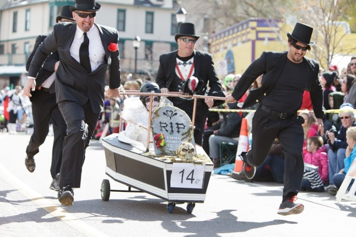 Men in pallbearer costumes racing with a fake coffin in the Emma Crawford Halloween events in Manitou Springs, CO