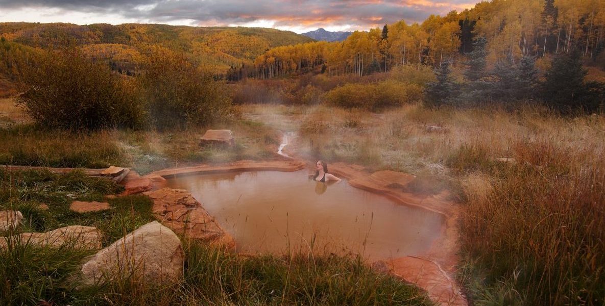 Woman soaking in hot springs outside in fall at Dunton Hot Springs