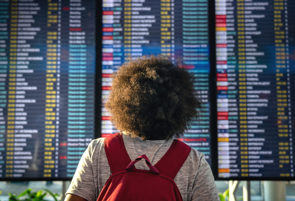 Man Looking at Arrivals and Departures Board at Airport