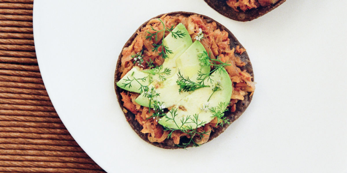 A pair of trout tostadas topped with slices of avocado