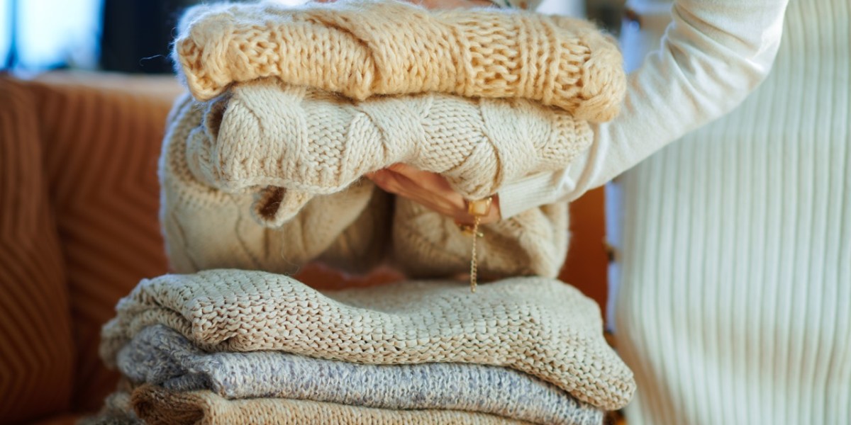 A close-up of a person stacking sweaters.