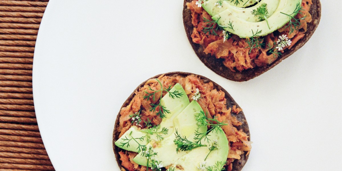 A pair of trout tostadas topped with slices of avocado