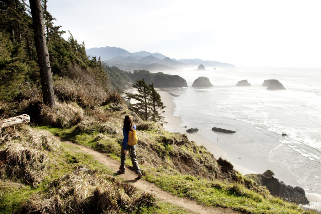 A woman hiking a path near the Oregon Coast with a Pacific Northwest trip