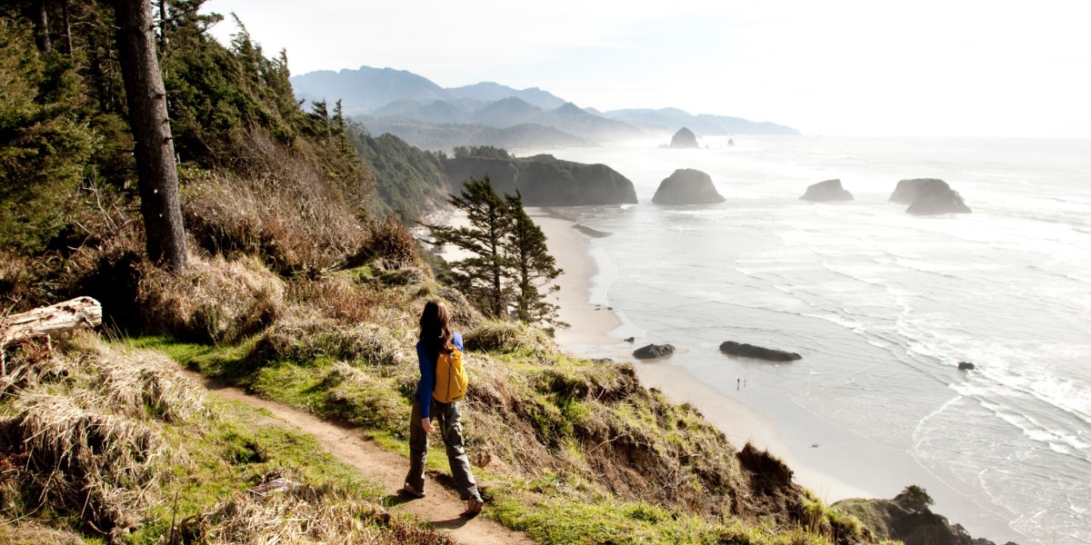 A woman hiking a path near the Oregon Coast with a Pacific Northwest trip