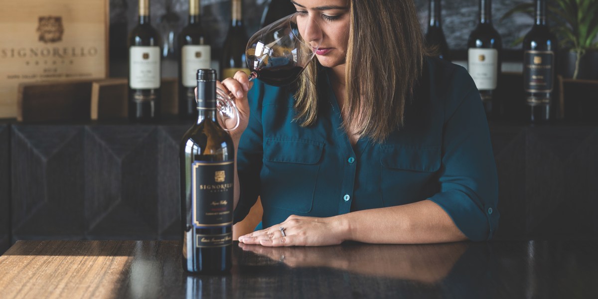 Signorello winemaker Priyanka French inhales aroma of glass of red wine with Signorello bottle on table