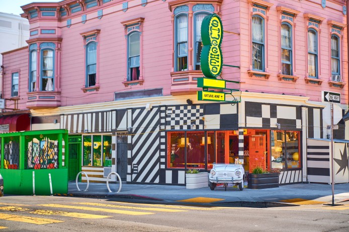 The exterior of a color restaurant featuring geometric patterns and a green and yellow sign with the name 