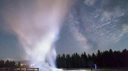 Father and son watch a Castle Geyser night eruption at Yellowstone National Park, one of the things you must see in Yellowstone