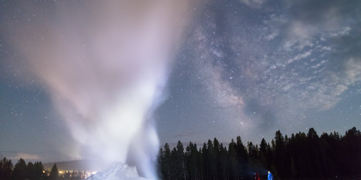 Father and son watch a Castle Geyser night eruption at Yellowstone National Park, one of the things you must see in Yellowstone